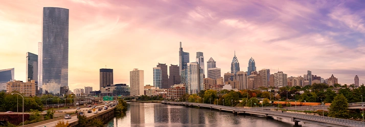 An iridescent city skyline highlighted by the pink and purple hues of dusk in Pennsylvania
